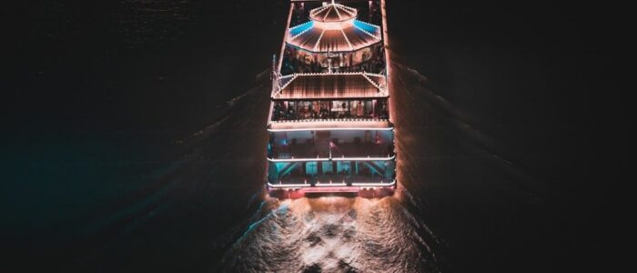 Verlicht passagiersschip vaart ’s nachts over donker binnenwater