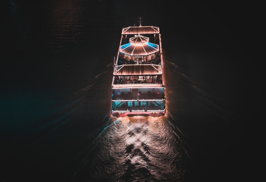 Verlicht passagiersschip vaart ’s nachts over donker binnenwater