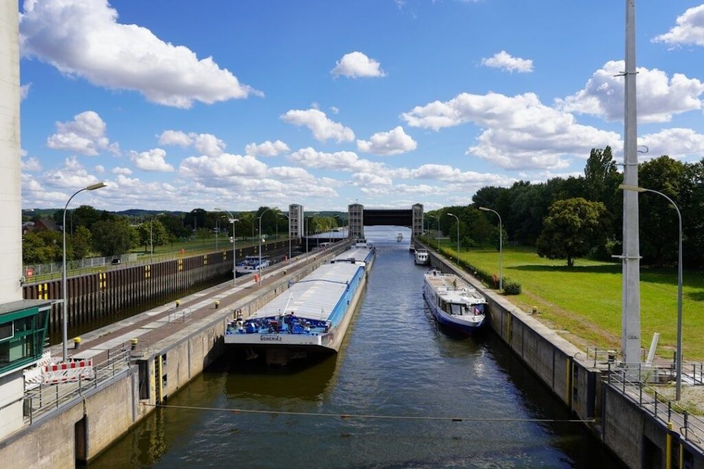 Vrachtschip en boten in een Europese schutsluis onder een blauwe hemel