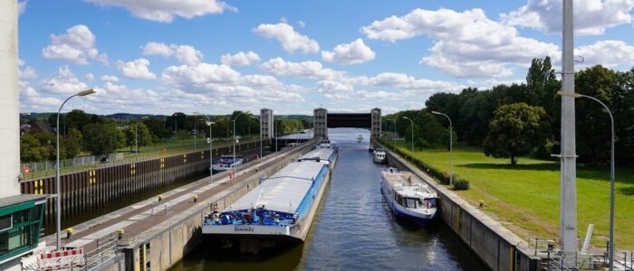 Vrachtschip en boten in een Europese schutsluis onder een blauwe hemel