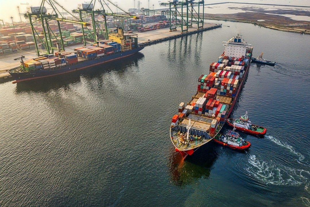 Containerschip wordt met sleepboten naar een havenkade begeleid