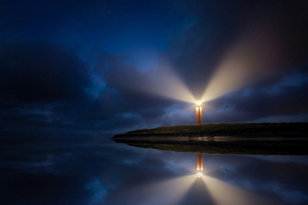 Verlichte vuurtoren met brede lichtbundels boven stilstaand water