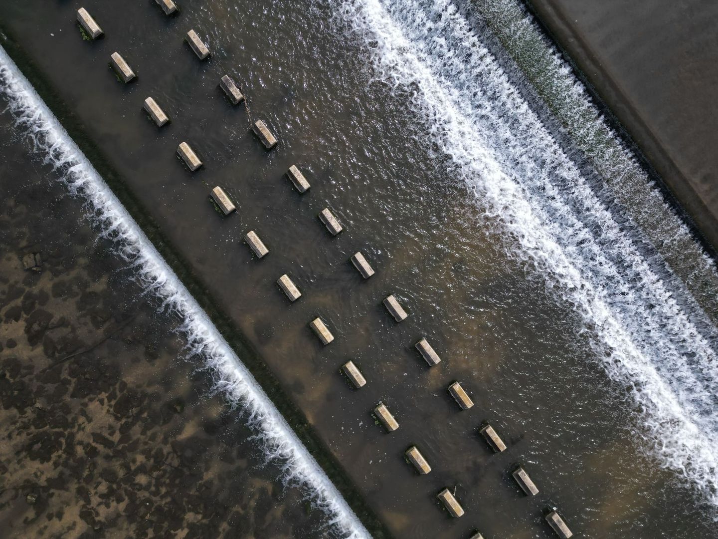 Luchtfoto van een stuw met kolkend water en betonnen balken