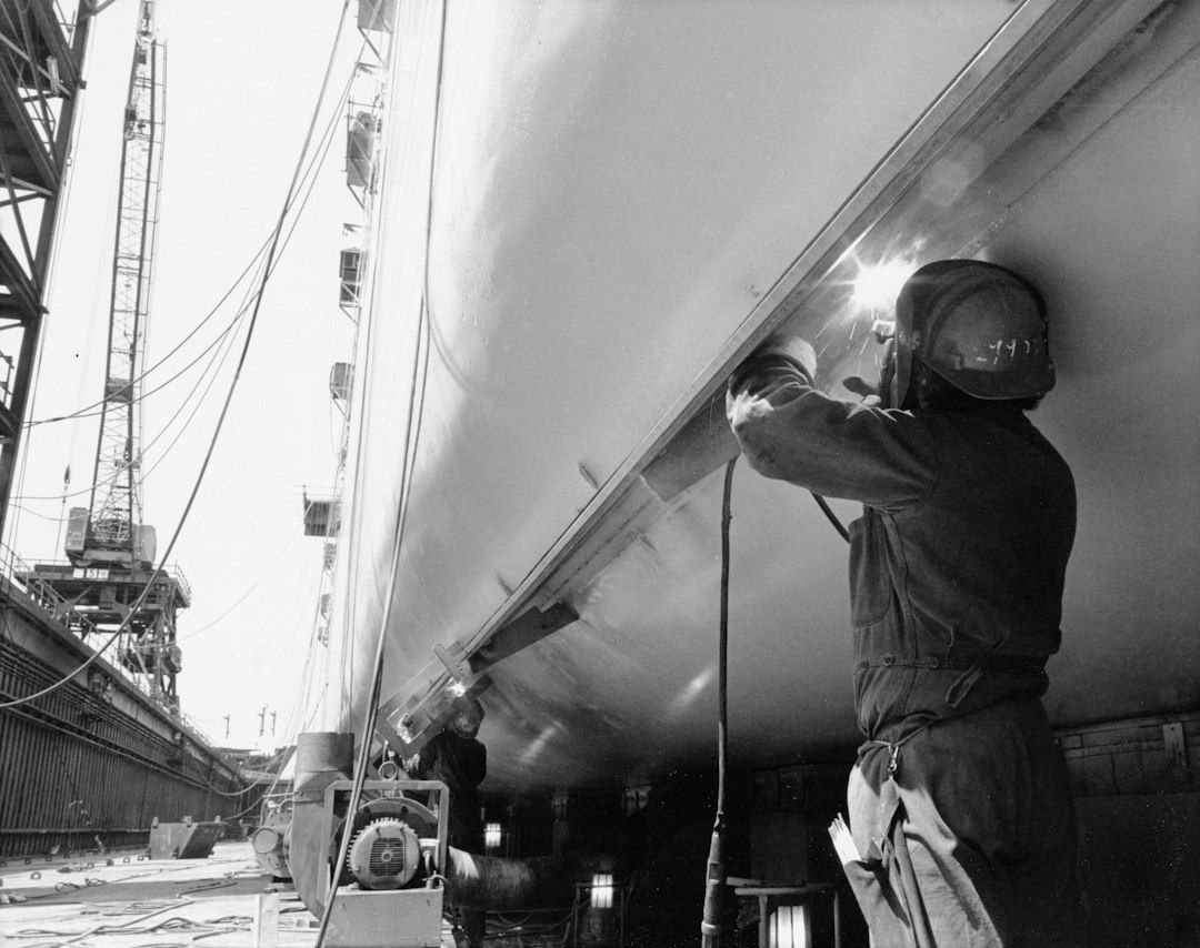 Lasser werkt aan de stalen romp van een schip in een scheepswerf
